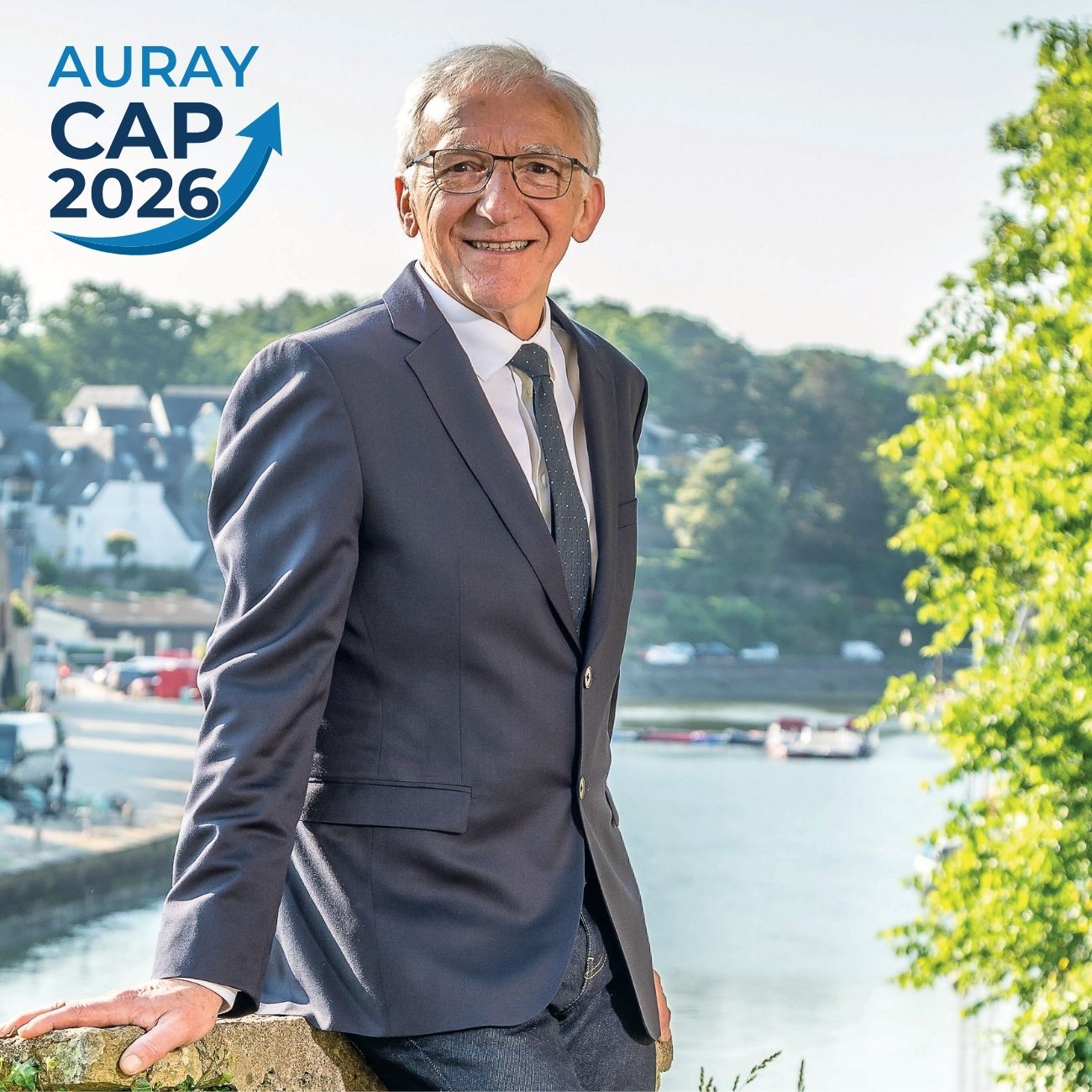 Portrait du candidat de la campagne Auray Cap 2026, en costume, souriant en extérieur à Auray avec la rivière en arrière-plan